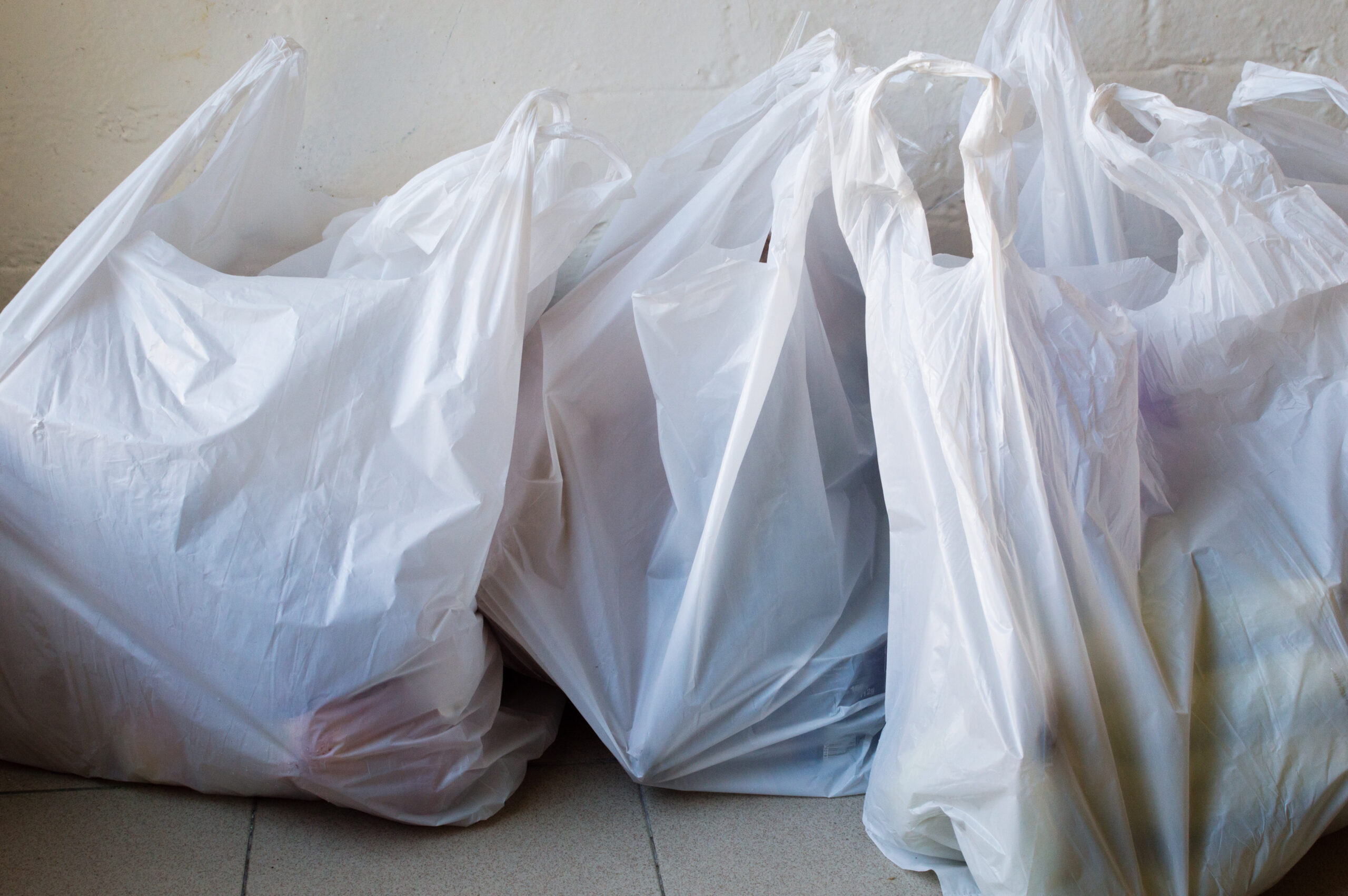 Full frame view of full plastic shopping bags on tiled floor Single-use plastic bags